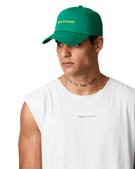 Man wearing a green cap and white t-shirt with text on a light gray background