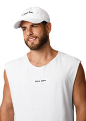 Man wearing a white sleeveless shirt and cap with text on a plain background