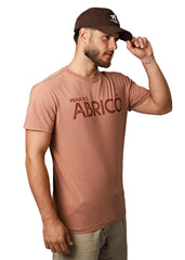 Man wearing a brown t-shirt with 'Praia do Abricó' text and a cap on a light gray background