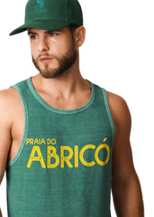 Man wearing a green tank top with 'Praia do AbricĂł' text and a matching cap.