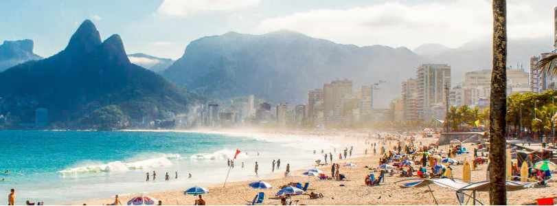 Beach scene with people, palm trees, and mountains in the background